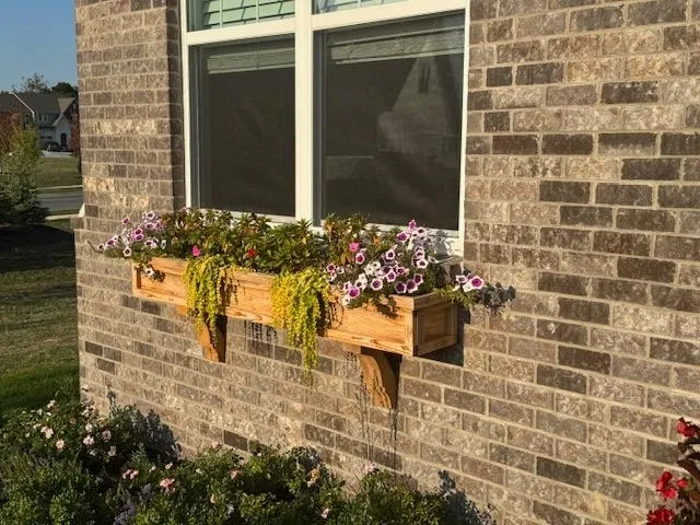 Cedar window box with flowering plants mounted on brick home exterior
